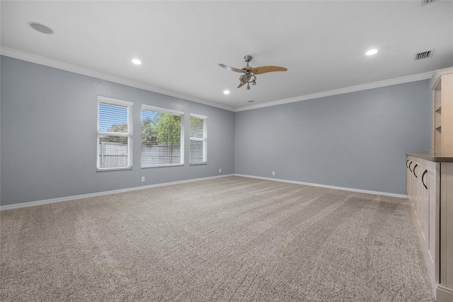 carpeted spare room with ceiling fan and crown molding