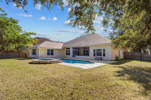 rear view of property featuring a patio, a yard, and a swimming pool with hot tub