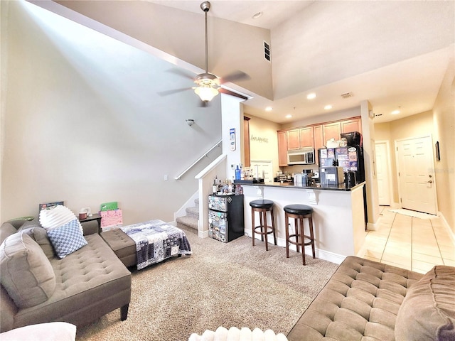 living room featuring ceiling fan, a high ceiling, and light carpet