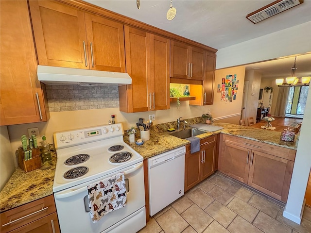 kitchen featuring light stone countertops, an inviting chandelier, sink, and white appliances