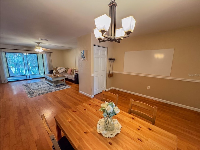 dining space featuring hardwood / wood-style flooring and ceiling fan with notable chandelier