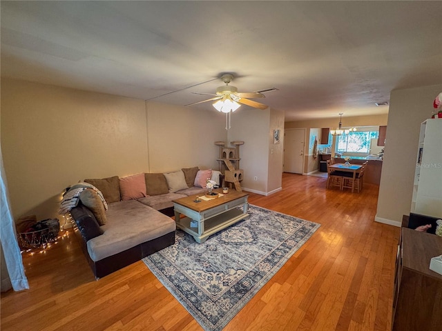 living room featuring ceiling fan with notable chandelier and hardwood / wood-style floors