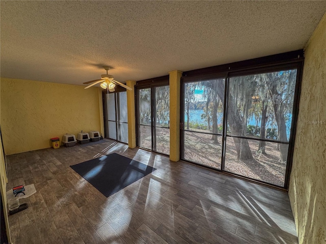 exercise area with ceiling fan, plenty of natural light, and a textured ceiling