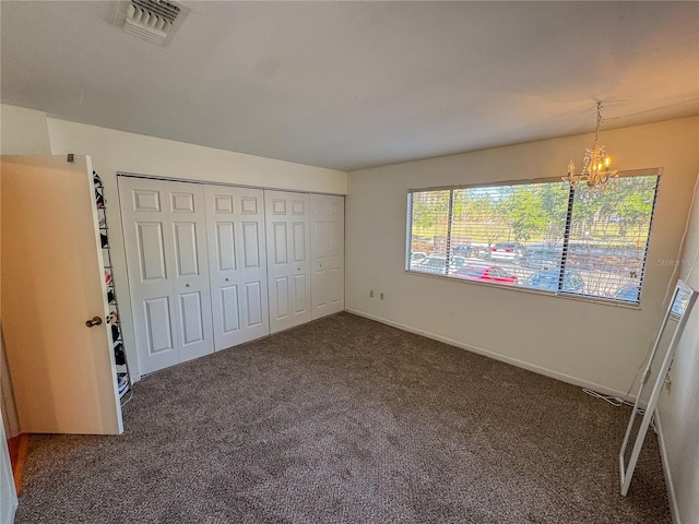 unfurnished bedroom featuring a closet, a chandelier, and dark colored carpet