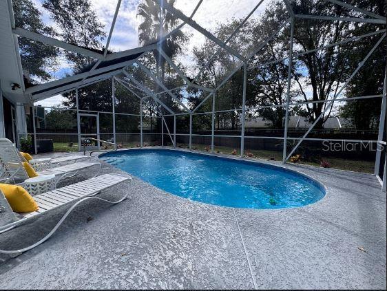 view of pool with a patio and glass enclosure