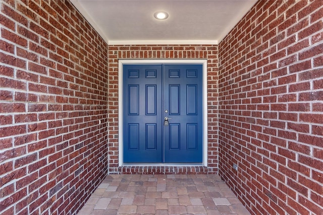 view of exterior entry featuring brick siding