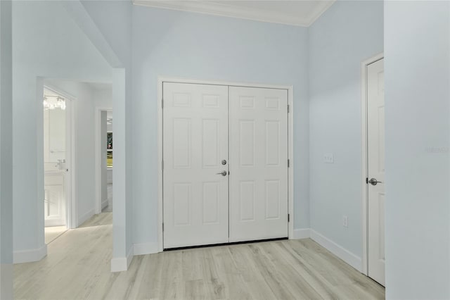 entrance foyer with light wood-style floors, ornamental molding, and baseboards