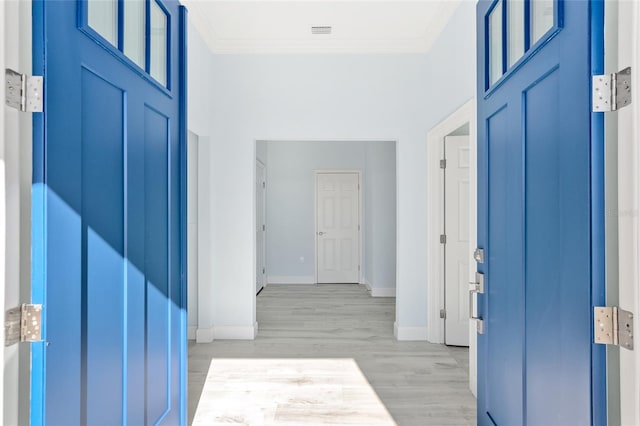 foyer entrance with ornamental molding, baseboards, light wood-style floors, and a high ceiling