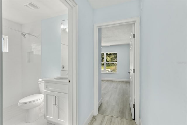 bathroom with visible vents, toilet, vanity, wood finished floors, and baseboards