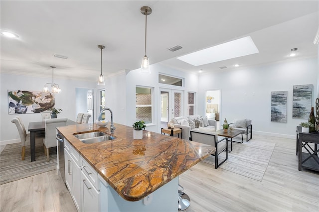 kitchen featuring visible vents, white cabinets, ornamental molding, a sink, and stainless steel dishwasher