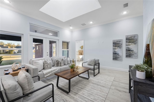 living area featuring ornamental molding, french doors, light wood-style flooring, and baseboards