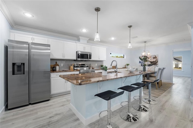 kitchen with appliances with stainless steel finishes, ornamental molding, and a kitchen breakfast bar