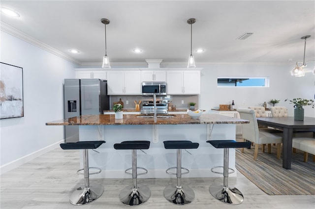 kitchen with a kitchen bar, a center island with sink, visible vents, and stainless steel appliances