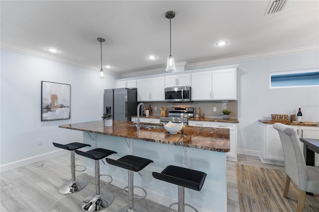 kitchen featuring white cabinets, decorative backsplash, a kitchen breakfast bar, stainless steel appliances, and a sink