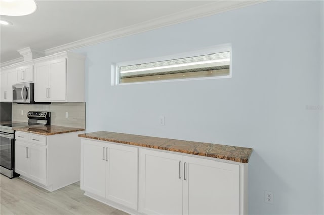 kitchen featuring tasteful backsplash, white cabinets, dark countertops, appliances with stainless steel finishes, and ornamental molding