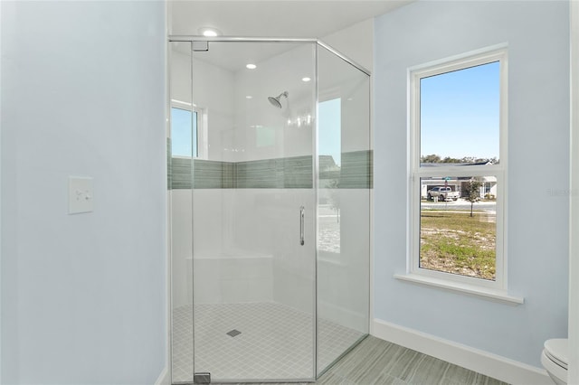 full bathroom with a stall shower, toilet, and baseboards