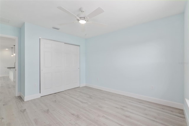 unfurnished bedroom featuring ceiling fan, visible vents, baseboards, light wood-style floors, and a closet