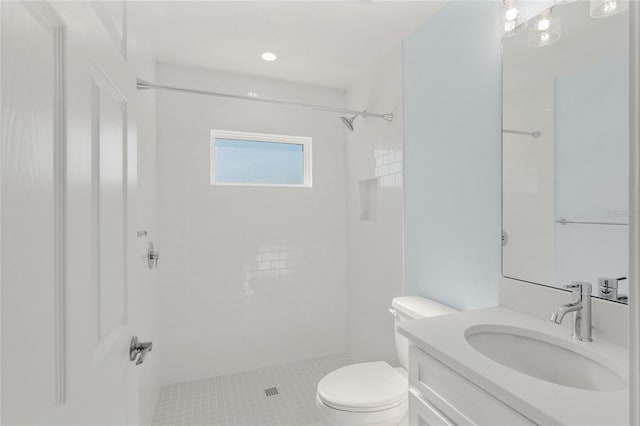 bathroom with tiled shower, vanity, and toilet