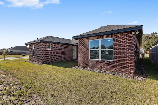 view of home's exterior featuring brick siding, a yard, and roof with shingles