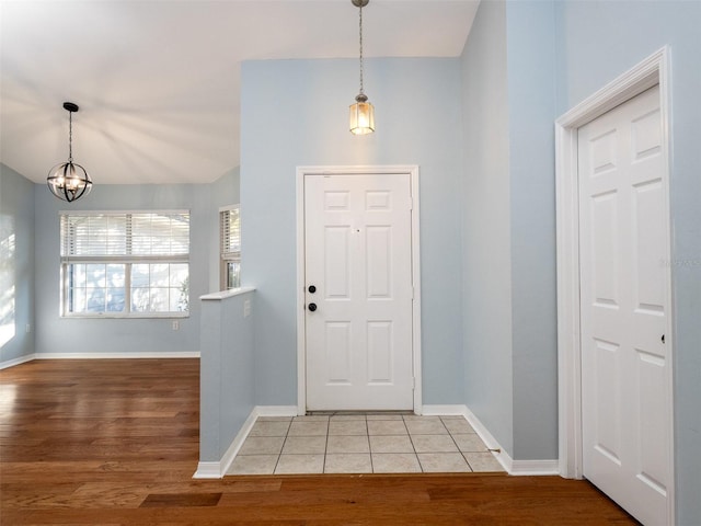 entryway with lofted ceiling, hardwood / wood-style flooring, and a notable chandelier