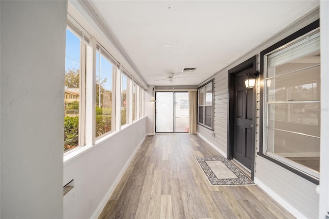 unfurnished sunroom featuring ceiling fan and a wealth of natural light