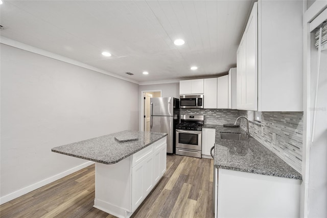 kitchen with appliances with stainless steel finishes, white cabinetry, a kitchen island, and sink