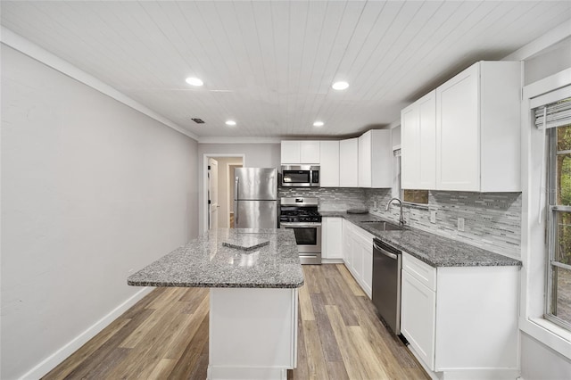 kitchen with appliances with stainless steel finishes, a center island, dark stone counters, sink, and white cabinetry