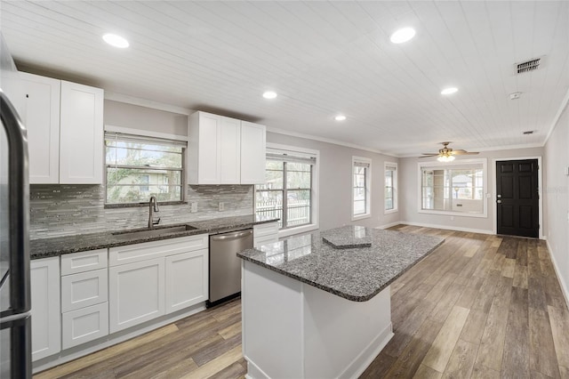 kitchen with stainless steel appliances, sink, a center island, white cabinetry, and backsplash