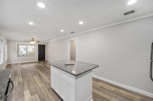 kitchen featuring a center island, light hardwood / wood-style floors, dark stone countertops, white cabinets, and ceiling fan