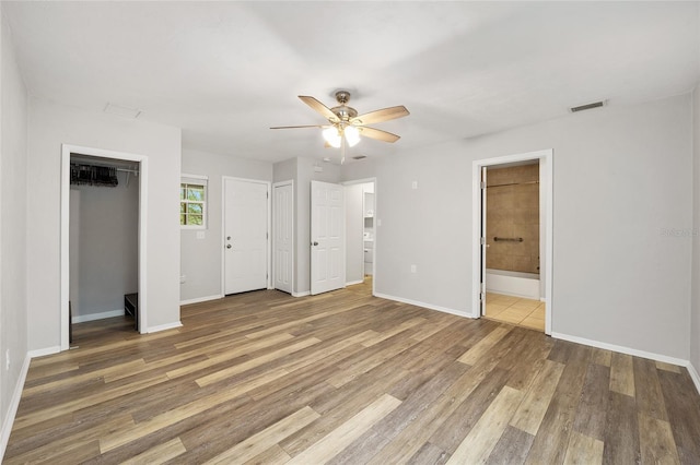 unfurnished bedroom with ensuite bath, ceiling fan, and hardwood / wood-style floors