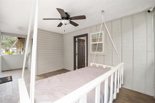 exterior space with a closet, ceiling fan, wood-type flooring, and wooden walls