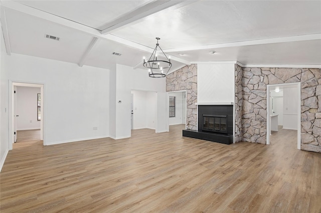 unfurnished living room featuring light hardwood / wood-style floors, a chandelier, lofted ceiling with beams, and a fireplace