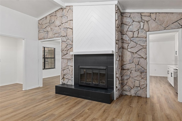 living room featuring a fireplace, light wood-type flooring, and lofted ceiling with beams