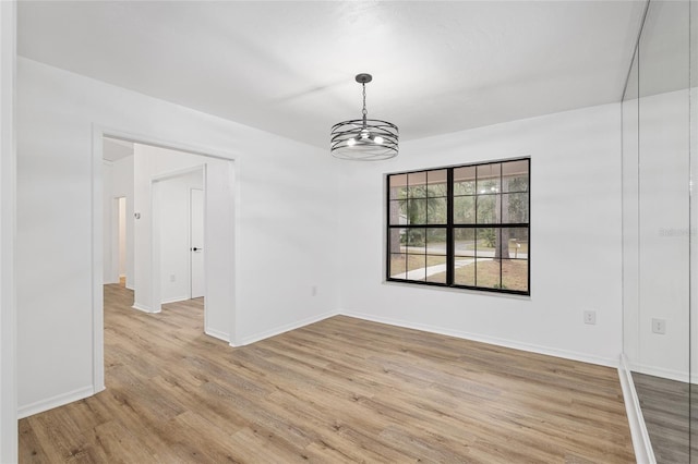 empty room featuring a chandelier and light hardwood / wood-style flooring