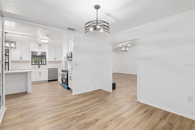 kitchen featuring white cabinets, hanging light fixtures, a notable chandelier, and appliances with stainless steel finishes