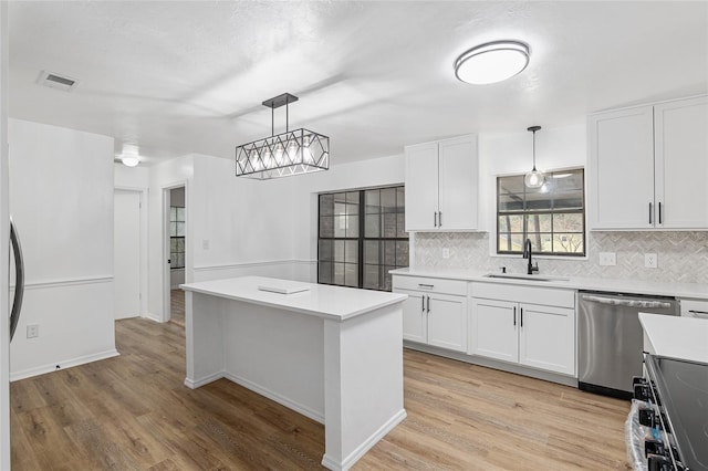 kitchen featuring appliances with stainless steel finishes, hanging light fixtures, a center island, sink, and white cabinetry