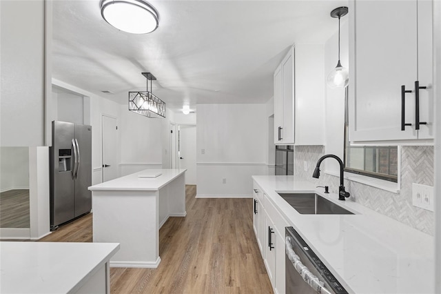 kitchen featuring sink, white cabinets, a center island, pendant lighting, and appliances with stainless steel finishes