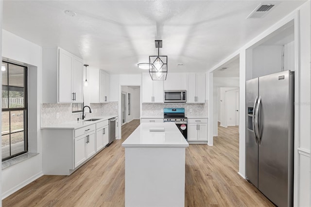 kitchen with a center island, hanging light fixtures, stainless steel appliances, decorative backsplash, and white cabinetry