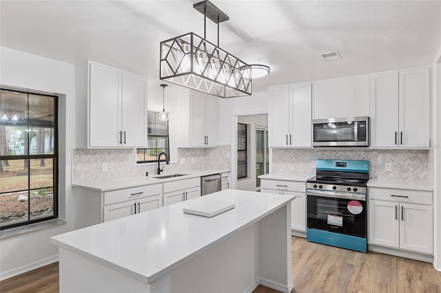 kitchen featuring sink, white cabinets, a kitchen island, pendant lighting, and appliances with stainless steel finishes