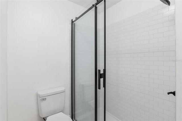 bathroom featuring toilet and a shower with shower door