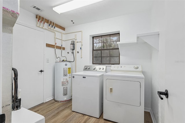 laundry area featuring water heater, light wood-type flooring, and washing machine and clothes dryer