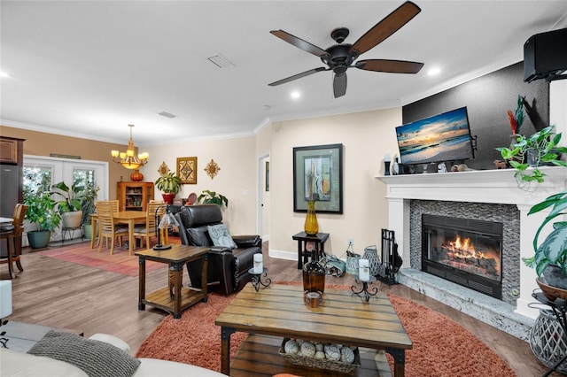 living room featuring ceiling fan with notable chandelier, ornamental molding, and light hardwood / wood-style floors