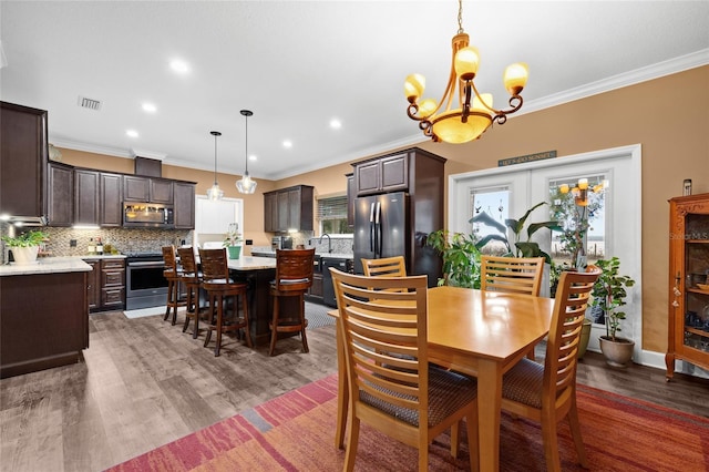 dining room with a notable chandelier, ornamental molding, sink, and dark hardwood / wood-style floors