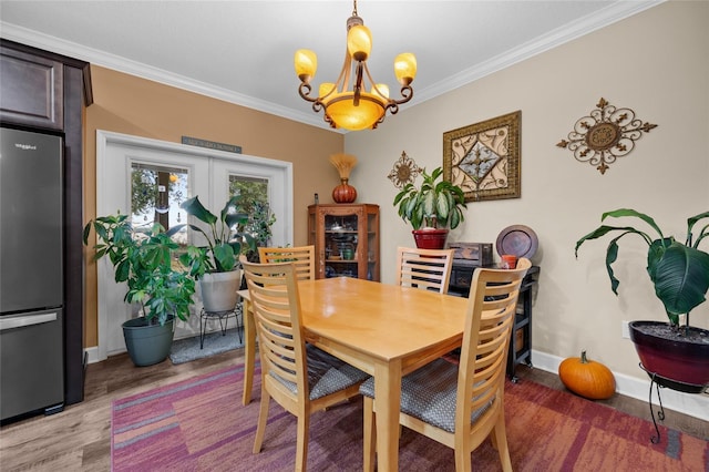 dining room featuring french doors, crown molding, hardwood / wood-style flooring, and a notable chandelier