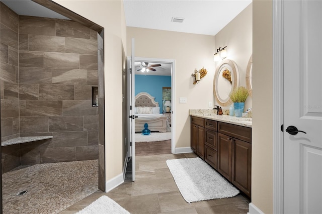 bathroom with tile patterned flooring, ceiling fan, tiled shower, and vanity