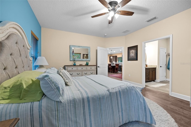 bedroom featuring ensuite bathroom, wood-type flooring, ceiling fan, and a textured ceiling