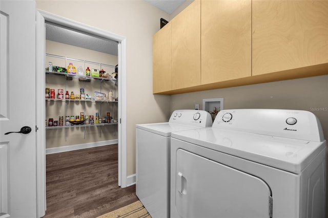 clothes washing area featuring a textured ceiling, dark wood-type flooring, cabinets, and washer and clothes dryer