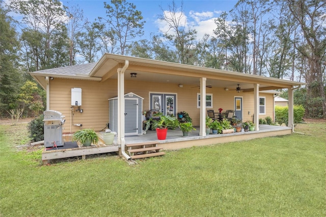 rear view of property with ceiling fan, a yard, and a shed