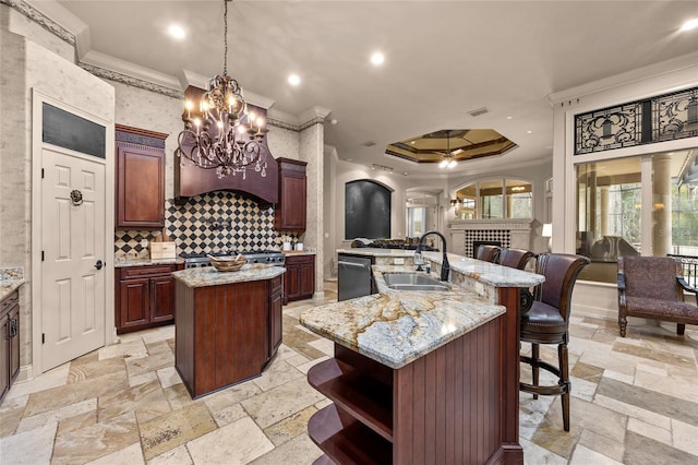 kitchen with sink, stainless steel dishwasher, crown molding, and a center island with sink