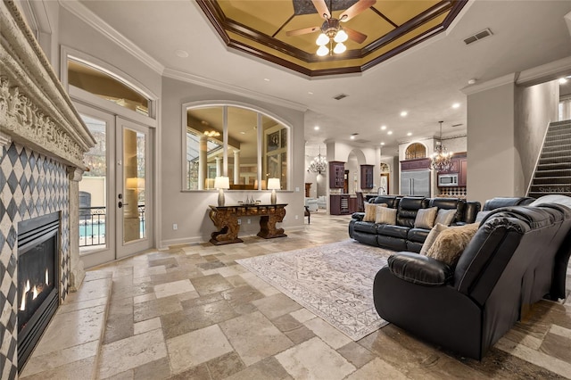 interior space with ceiling fan with notable chandelier, ornamental molding, and a tray ceiling